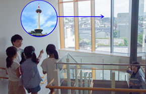 階段の一番上から窓の向こうを見ると、ずっと南の方に京都タワー発見！