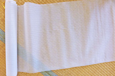 長艸氏たちが復元した「羅」。畳が透け見える。うっすら菱形の紋様が見える。