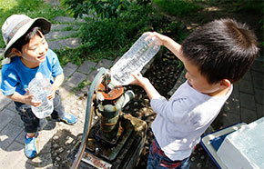 鴨川デッキにある手押しポンプを使って、本当に水が出るのを実験している様子