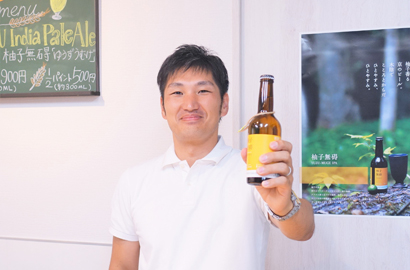 クラフトビール柚子無碍(ゆうずうむげ）を掲げる松尾さん