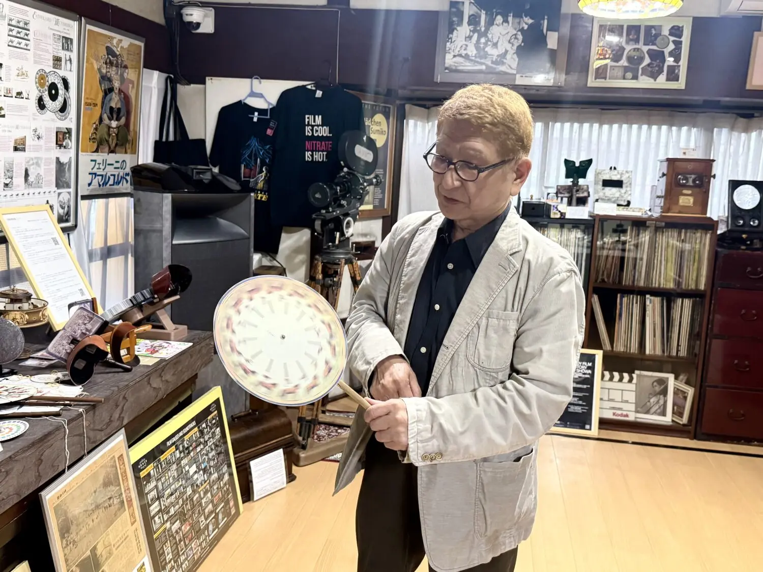 プレ・シネマと位置付けされる光学玩具「フェナキスティスコープ」を手に取り説明する米男さん。